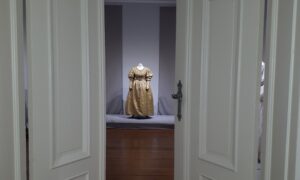 zdjęcie sali, w głębi stoi suknia z lat 30. XIX wieku